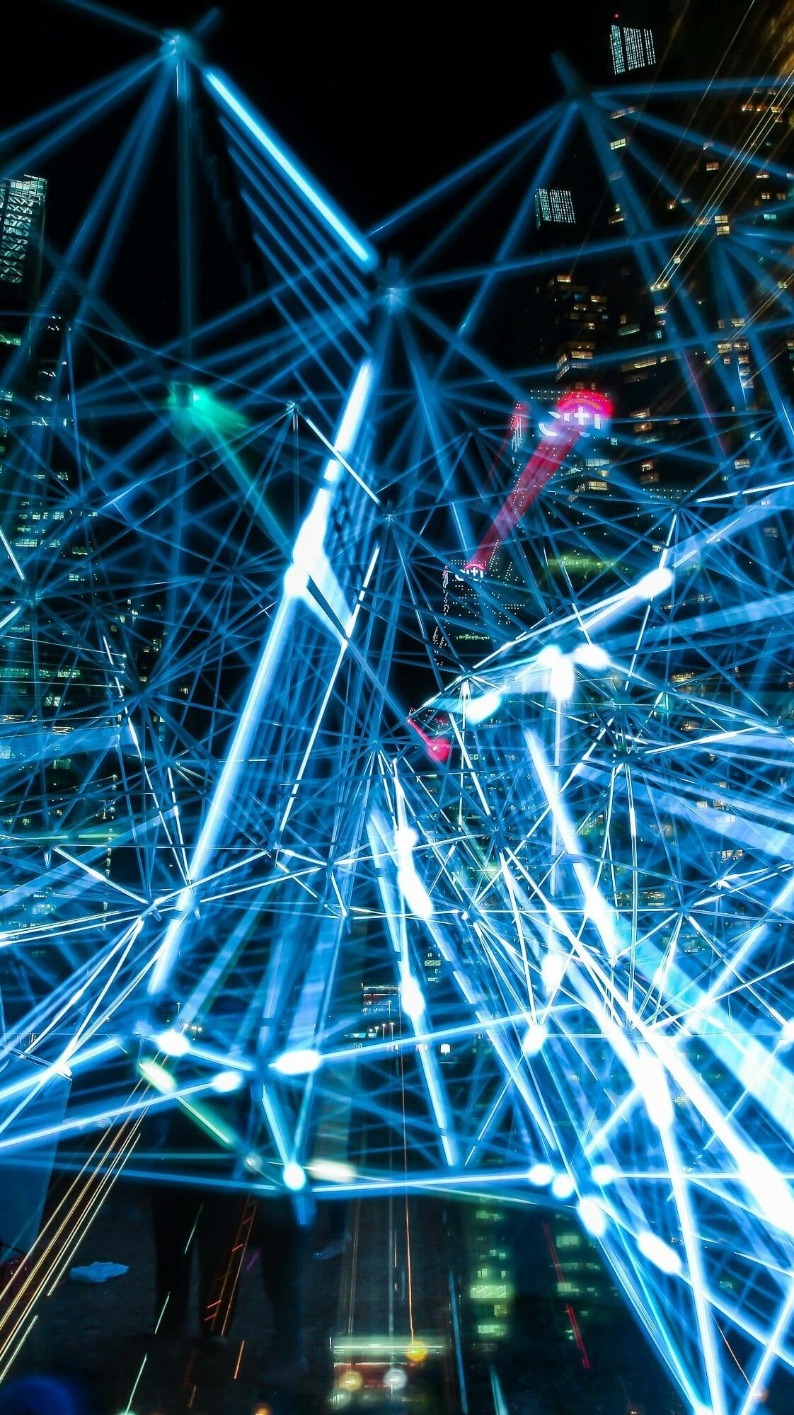 Aerial view of bright neon digital data connection lines over a cityscape at night
