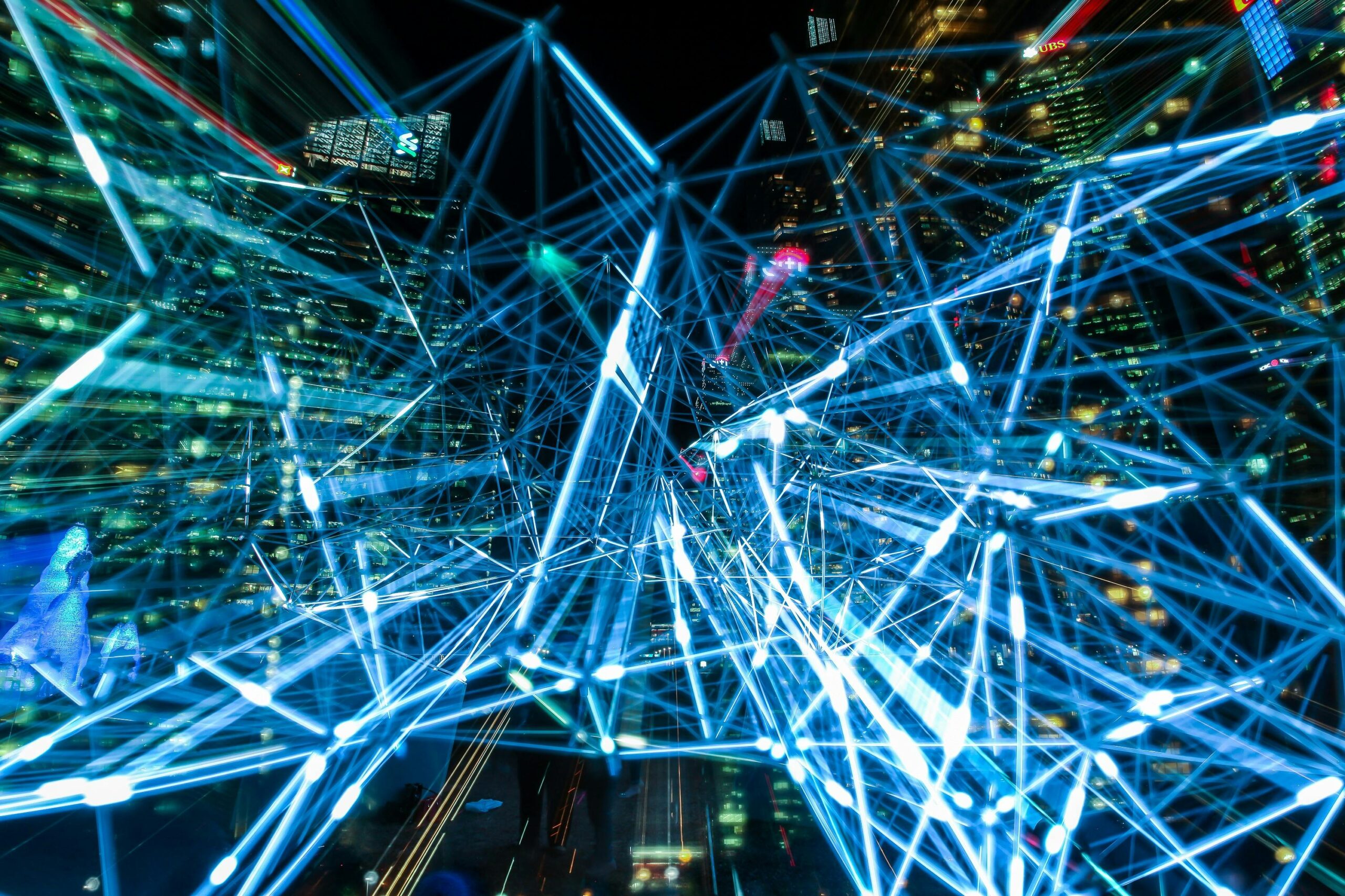 Aerial nighttime city view with glowing blue interconnected data network lines