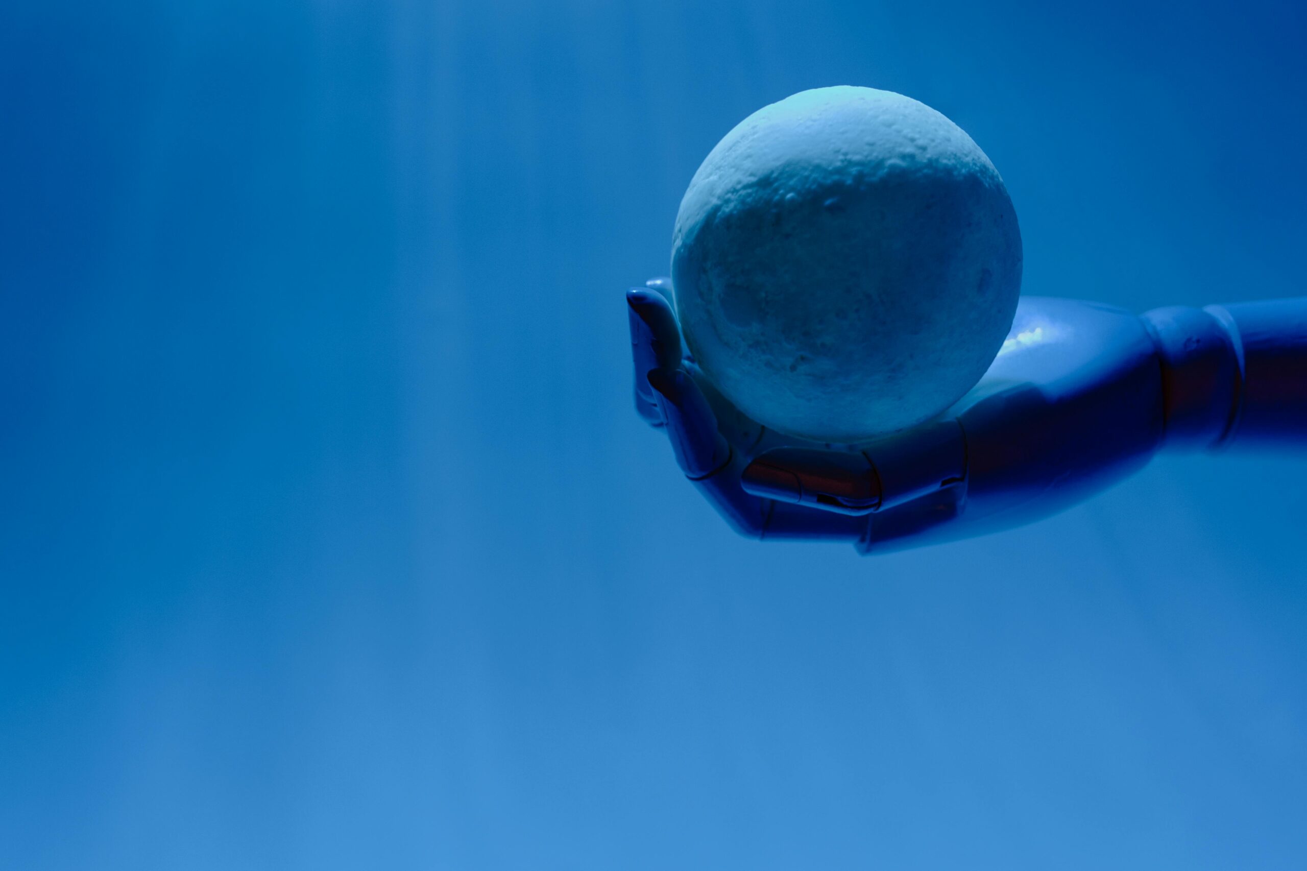 Blue robotic arm reaching toward a glowing digital orb