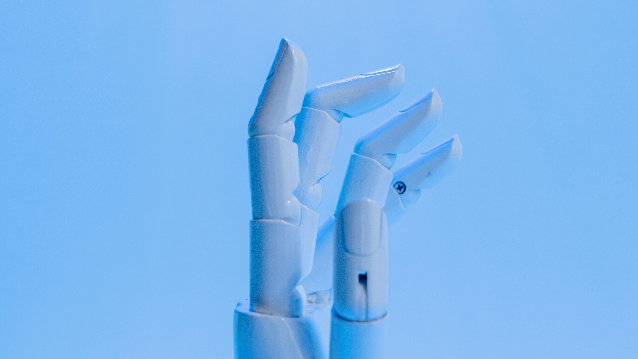 White articulated robotic hand with mechanical finger joints against a light blue background