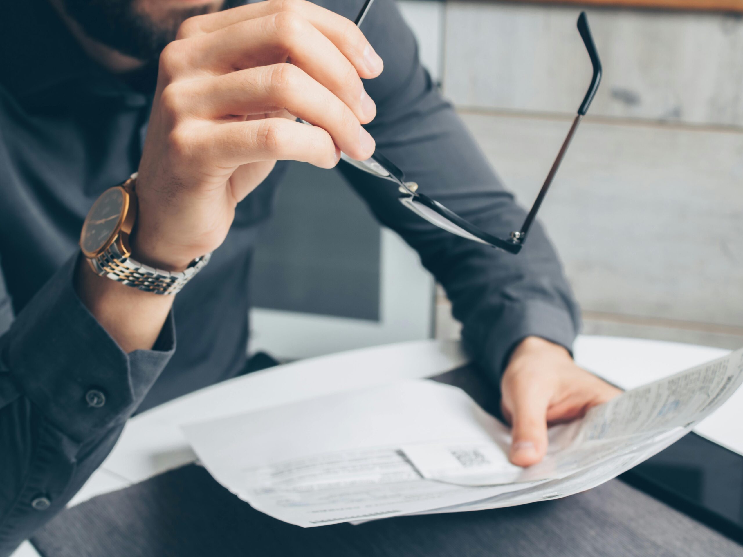 Close-up of a professional adjusting glasses while reviewing printed documents